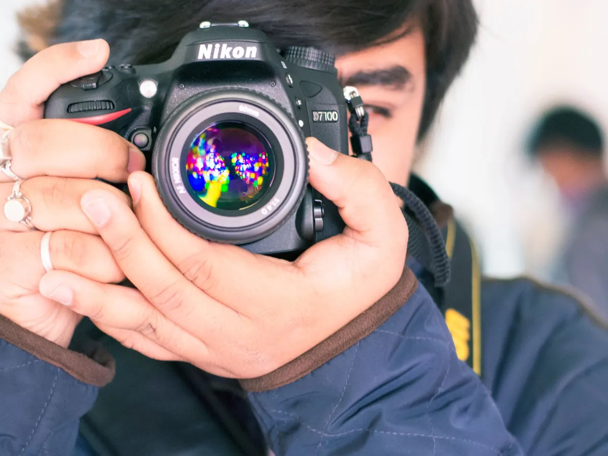 Fotograaf houdt een Nikon-spiegelreflex met lichtsterk objectief voor het gezicht
