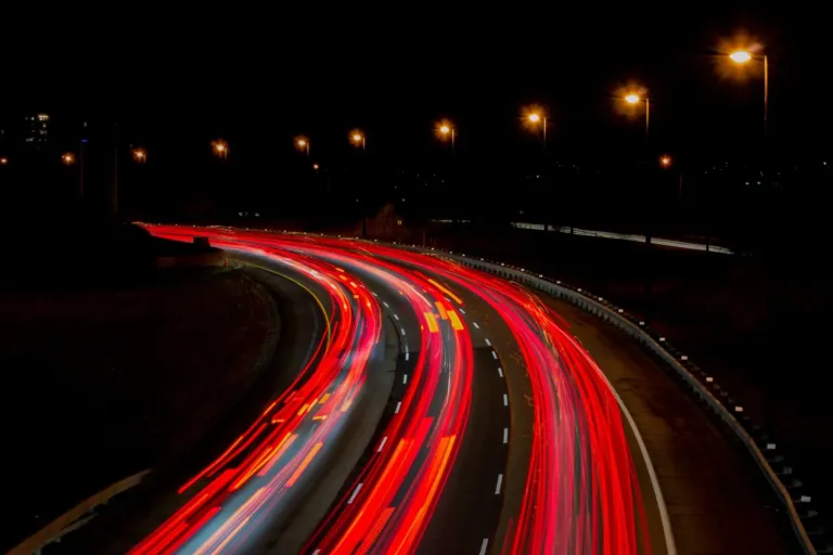 Rode en witte lichtsporen van auto's op een bochtige snelweg bij nacht, gemaakt met een lange sluitertijd