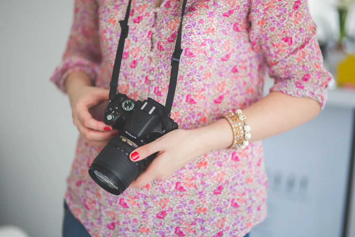 Vrouw houdt een compacte Nikon spiegelreflex met zoomobjectief vast