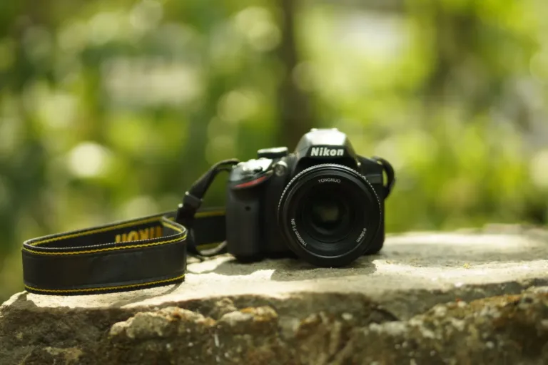 Compacte Nikon spiegelreflexcamera met objectief en draagriem op een rots buiten