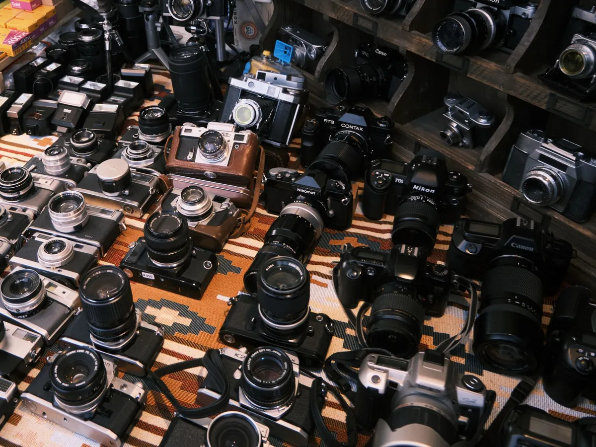 Veel gebruikte analoge en digitale camera's naast elkaar uitgestald op een kleed