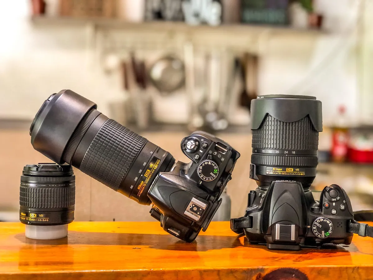 Twee Nikon-spiegelreflexcamera's met zoomobjectieven op een oranje tafelblad