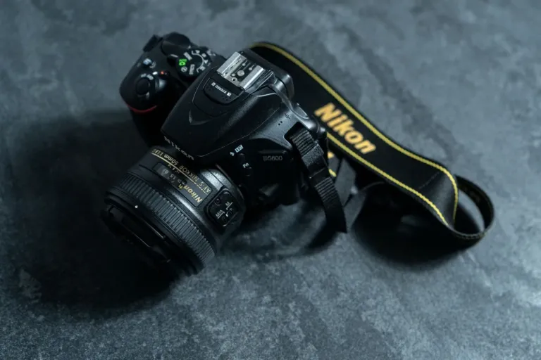 Nikon spiegelreflexcamera met objectief en draagriem op een grijze stenen ondergrond