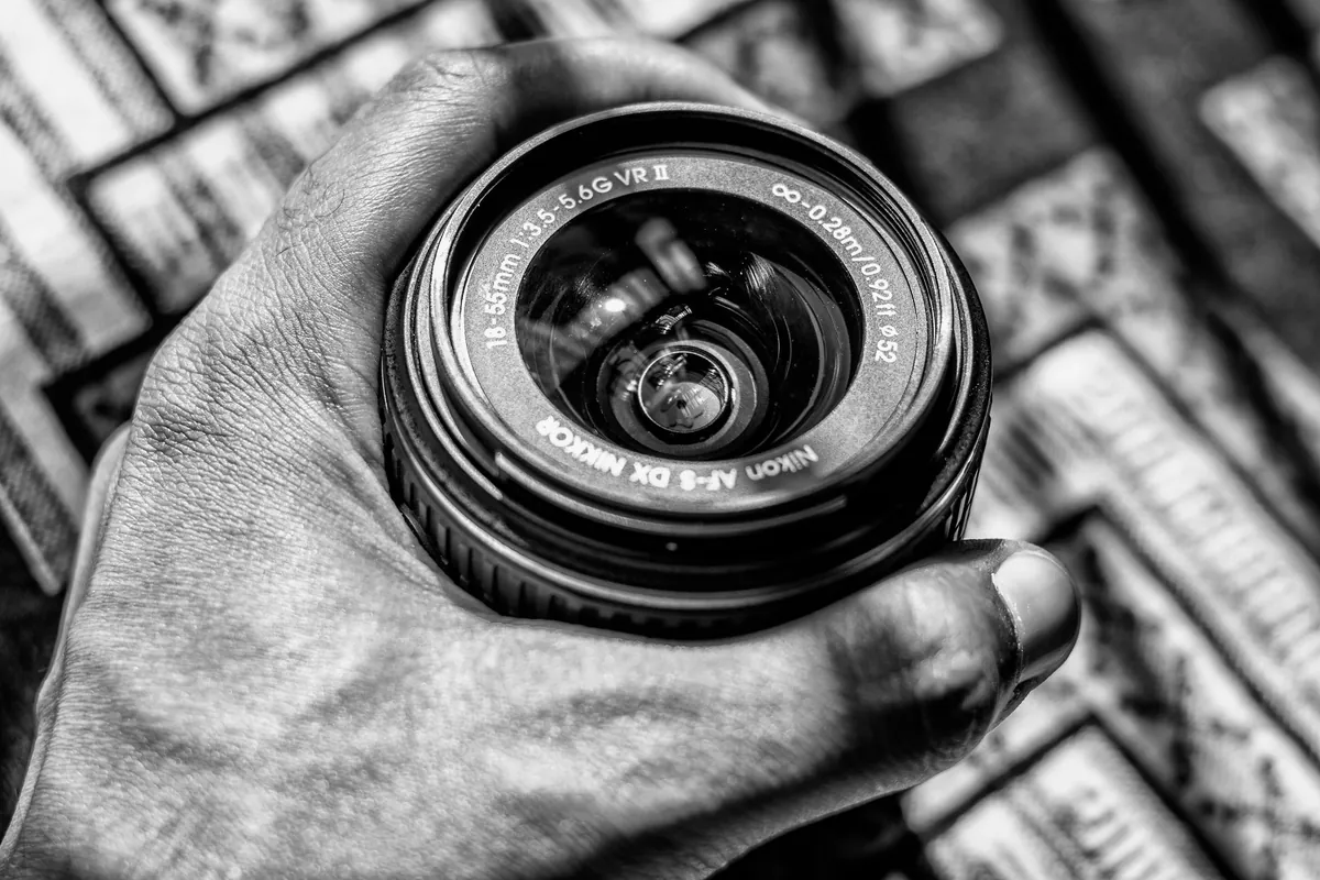 Zwart-witfoto van een hand die een Nikon AF-S DX-zoomobjectief vasthoudt