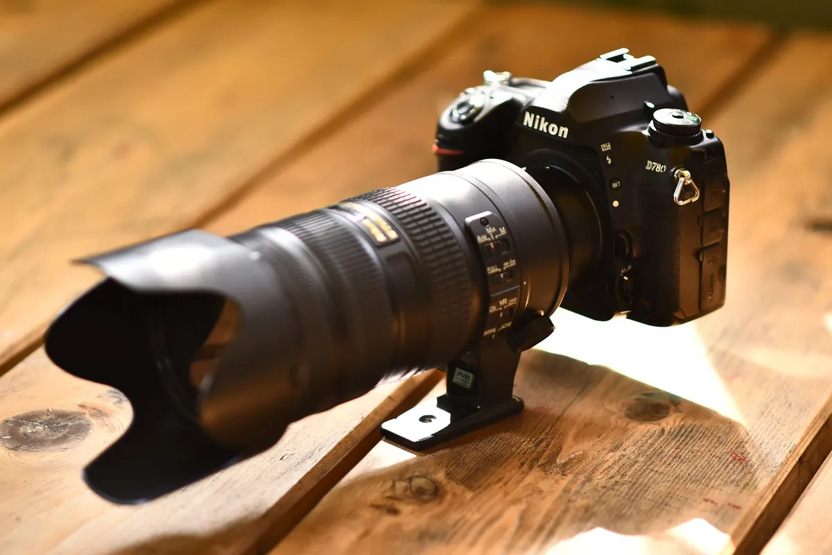 Nikon spiegelreflexcamera met een groot telezoomobjectief en zonnekap op een houten tafel